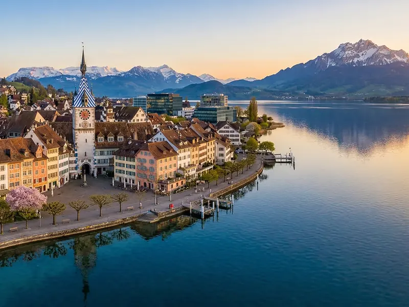 Blick auf die Stadt Zug am See bei Sonnenuntergang mit den Alpen im Hintergrund